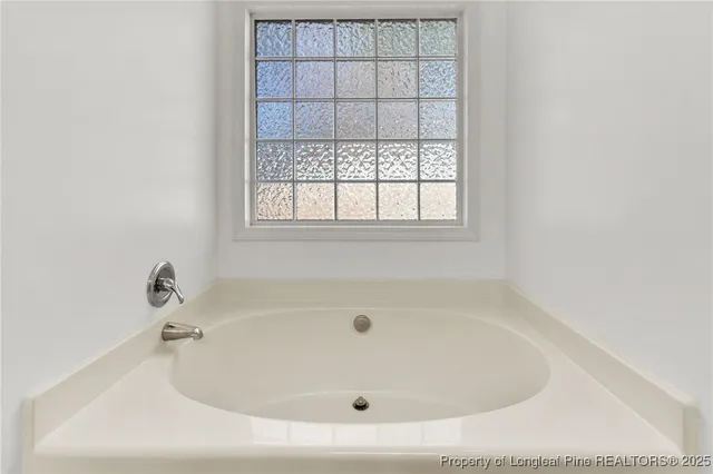a white bath tub sitting in a bathroom next to a window