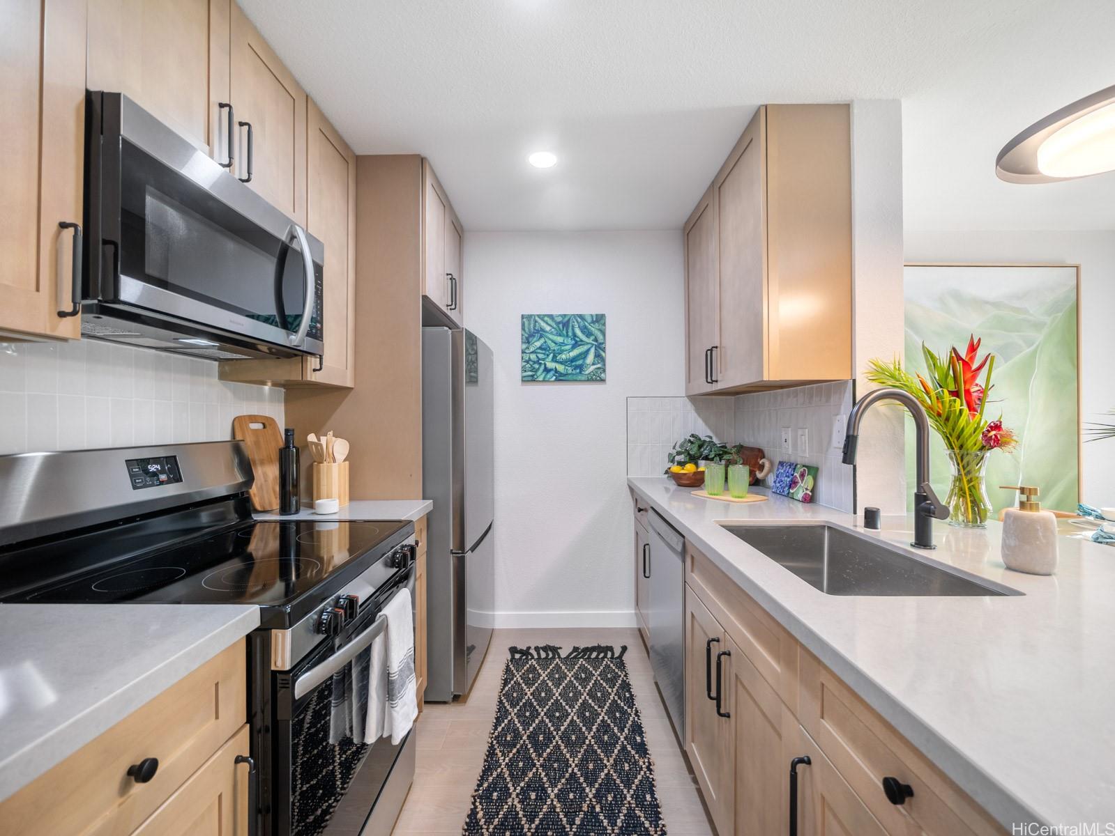 95-664 Wikao Street, Unit L205 Mililani, HI 96789 - Photo 5 of 25 a kitchen with stainless steel appliances a sink a stove a microwave a sink and cabinets
