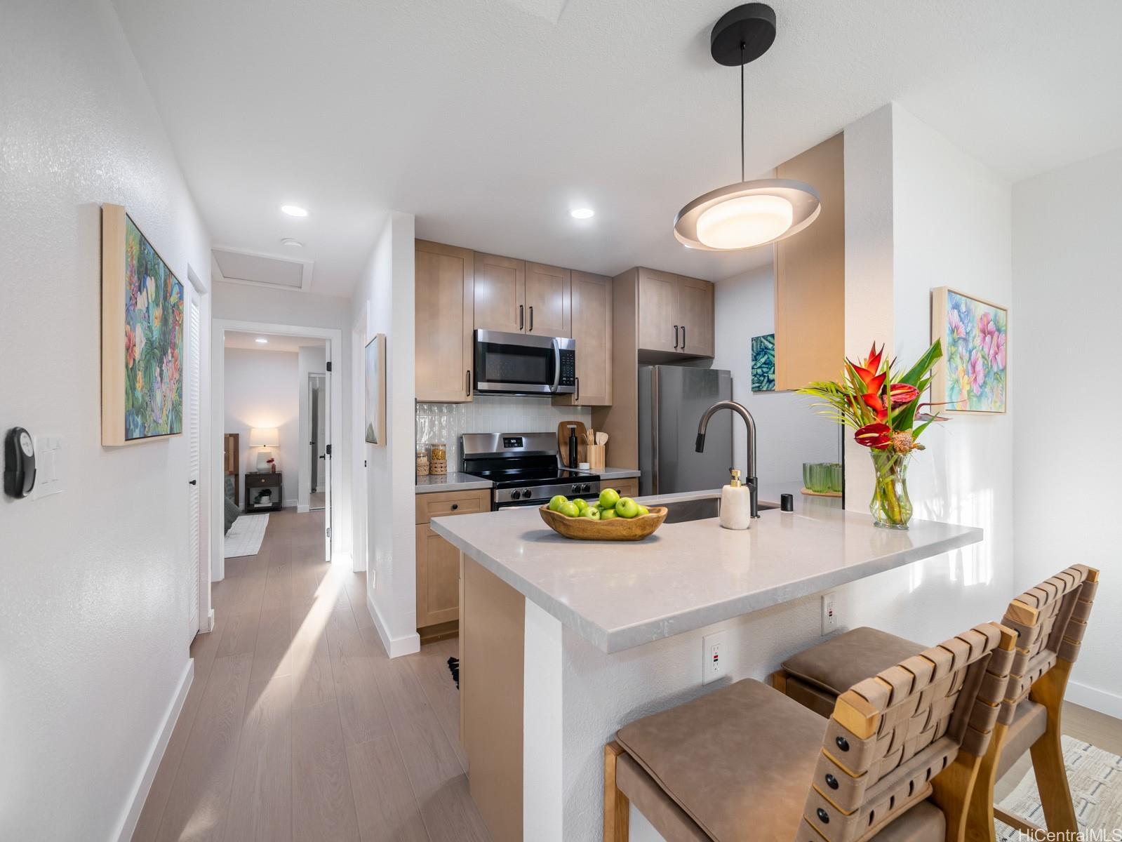 95-664 Wikao Street, Unit L205 Mililani, HI 96789 - Photo 6 of 25 a kitchen with stainless steel appliances granite countertop a refrigerator a stove a sink a dining table and chairs with wooden floor