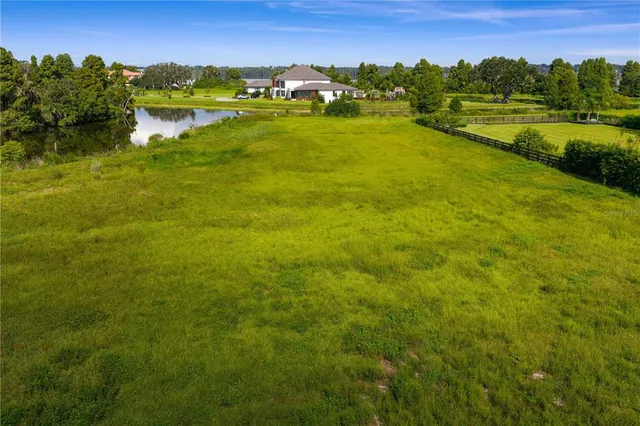 a view of a big house with a big yard and large trees