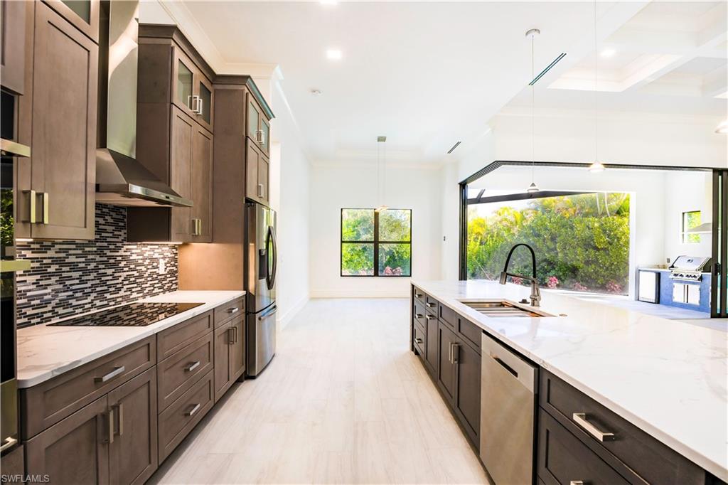 231 Legacy Court Naples, FL 34110 - Photo 14 of 35 a large kitchen with stainless steel appliances a sink and cabinets