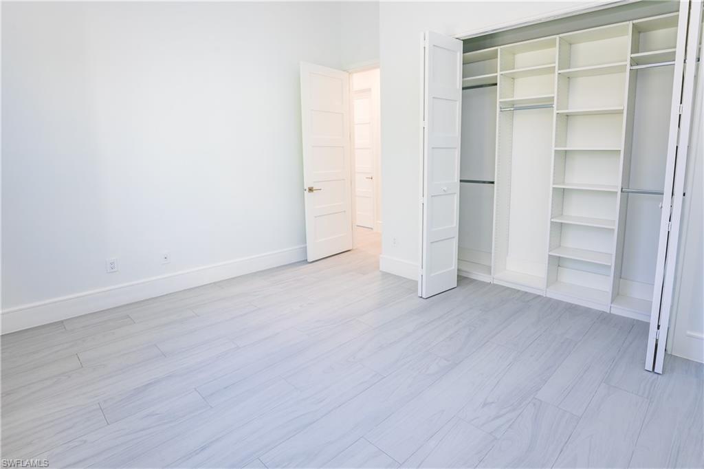231 Legacy Court Naples, FL 34110 - Photo 18 of 35 a view of an empty room with closet and wooden floor
