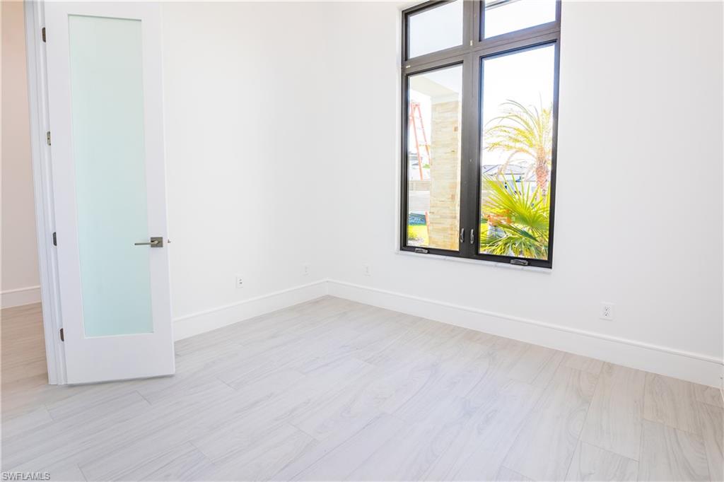 231 Legacy Court Naples, FL 34110 - Photo 21 of 35 an empty room with a window and wooden floor