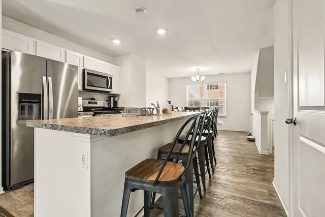 a kitchen with kitchen island a refrigerator and a dining table