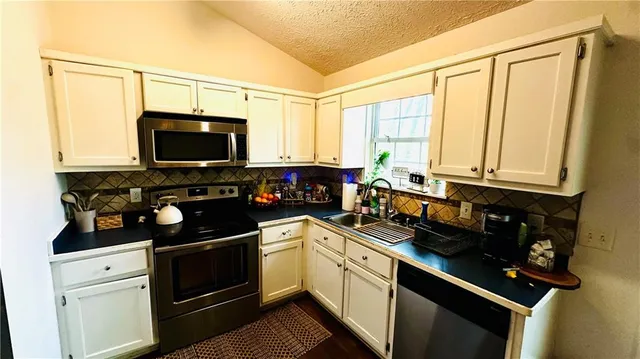 a kitchen with stainless steel appliances a stove a sink and a microwave