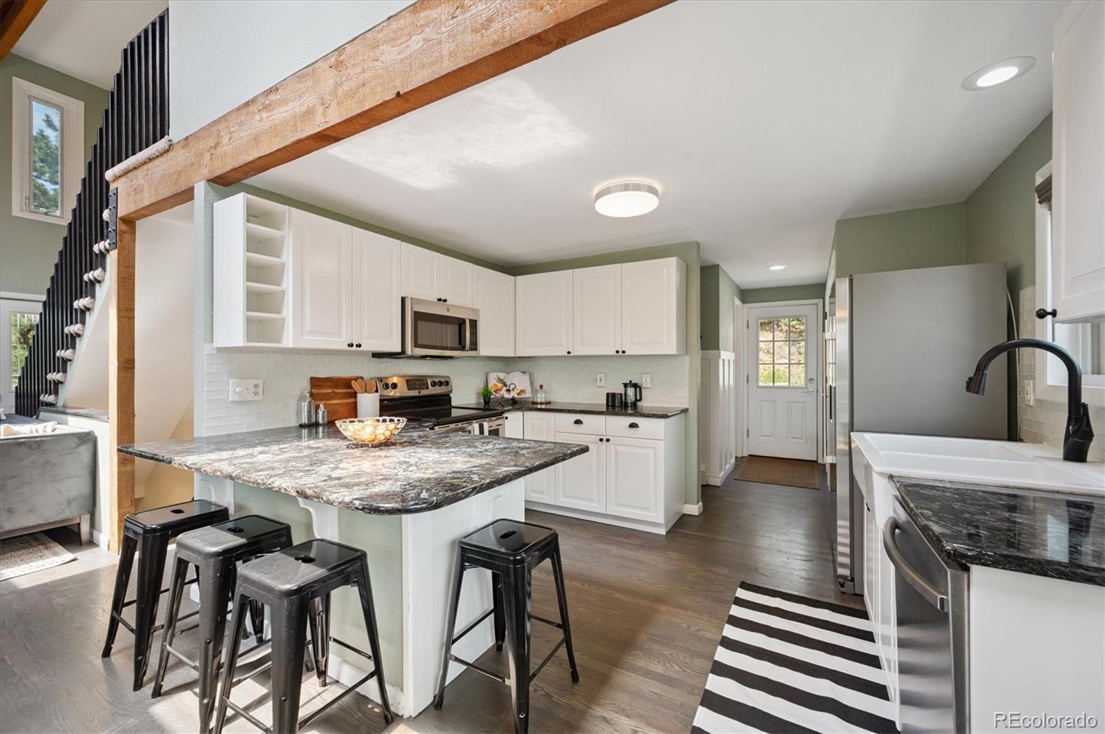 9189 Fallen Rock Road Conifer, CO 80433 - Photo 10 of 47 a kitchen with stainless steel appliances granite countertop a kitchen island hardwood floor sink stove dining table and chairs