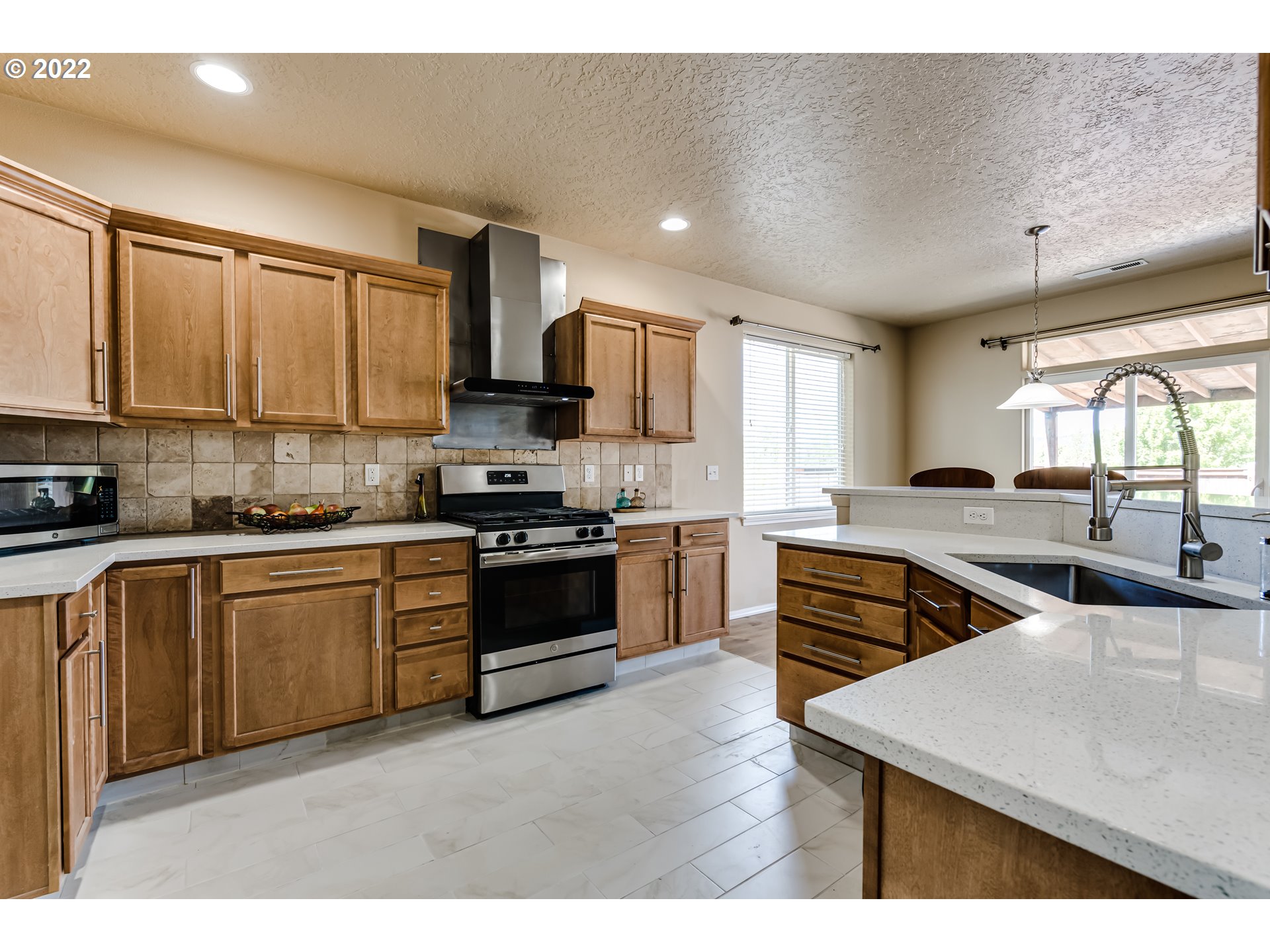507 South 48th Place Springfield, OR 97478 - Photo 12 of 31 a kitchen with stainless steel appliances kitchen island granite countertop a stove top oven a sink a dining table and chairs