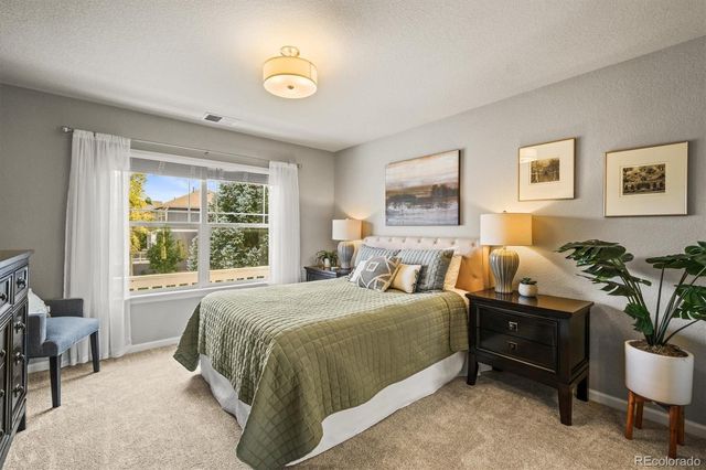a bedroom with a bed potted plant on table and window