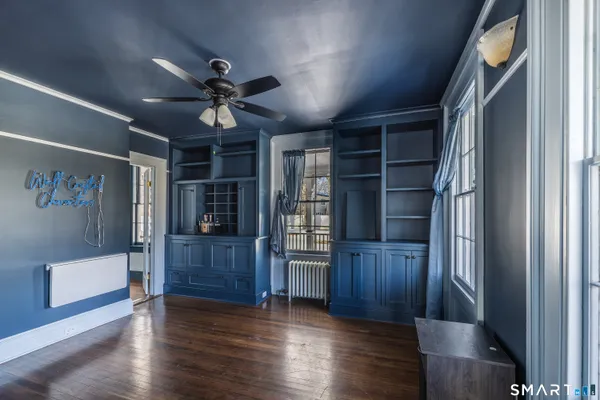 a view of empty room with wooden floor and fan