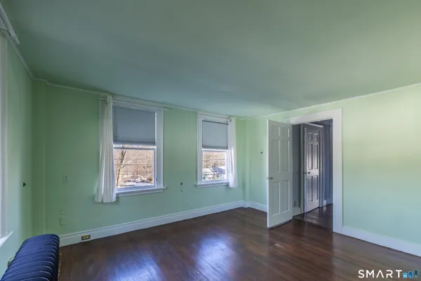 an empty room with wooden floor closet and windows