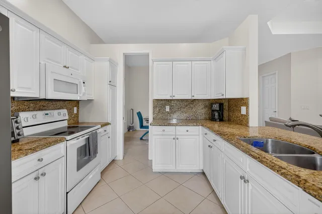 a kitchen with white cabinets appliances and a sink