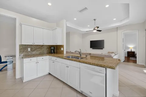a open kitchen with kitchen island granite countertop a sink and white cabinets