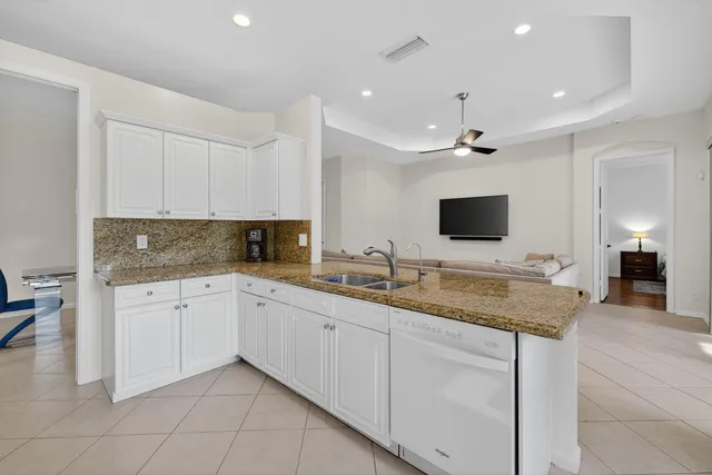 a open kitchen with kitchen island granite countertop a sink and white cabinets