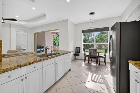 a large kitchen with kitchen island granite countertop a large window and white appliances