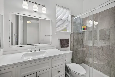 a bathroom with a sink a toilet a mirror and shower