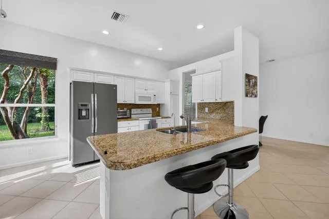 a kitchen with stainless steel appliances granite countertop a sink and a refrigerator