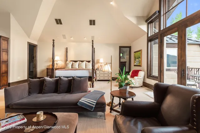 a bedroom with a bed a mirror on the wall and a large window