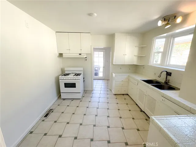 a kitchen with granite countertop a stove a sink and a refrigerator