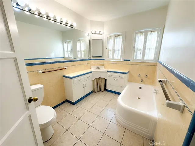 a spacious bathroom with a granite countertop sink mirror vanity bathtub and toilet