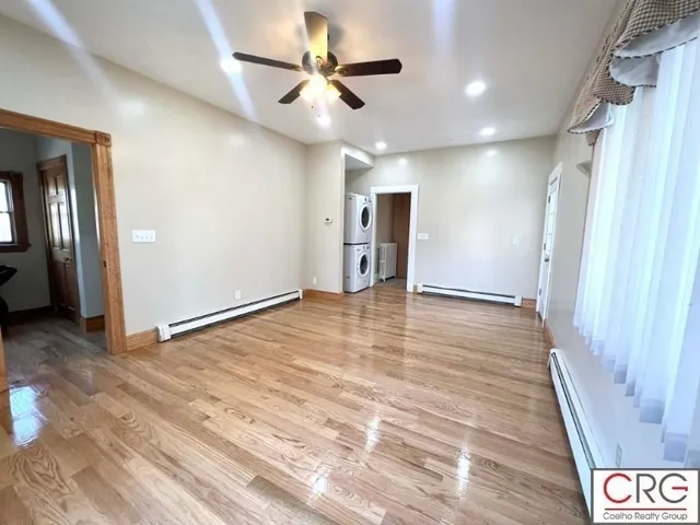 an empty room with wooden floor and a ceiling fan