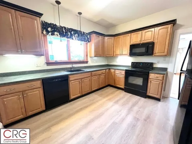 a kitchen with stainless steel appliances granite countertop wooden cabinets a sink a stove a refrigerator and island with wooden floor