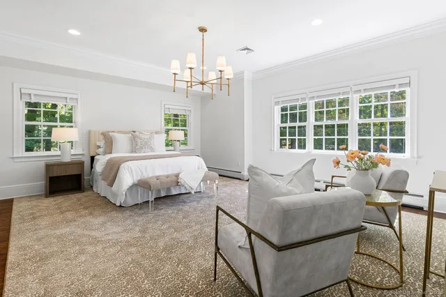 a spacious bedroom with a bed a couch and chandelier