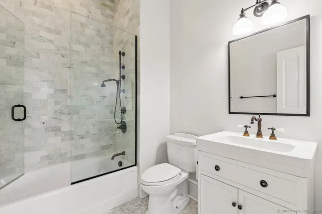 a bathroom with a toilet sink a mirror and shower