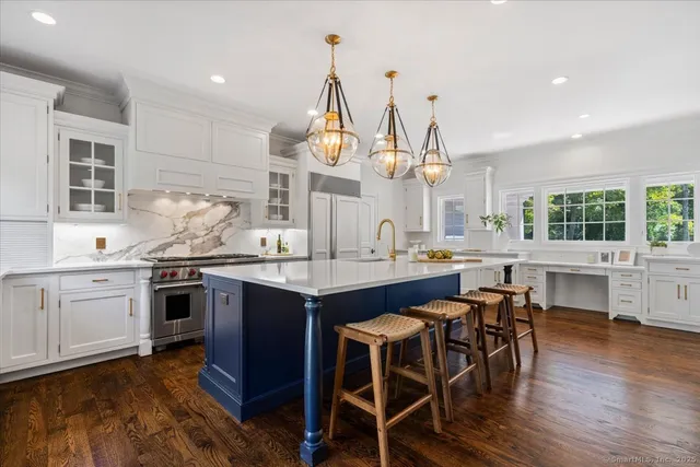 a kitchen with stainless steel appliances granite countertop wooden floor window and chairs