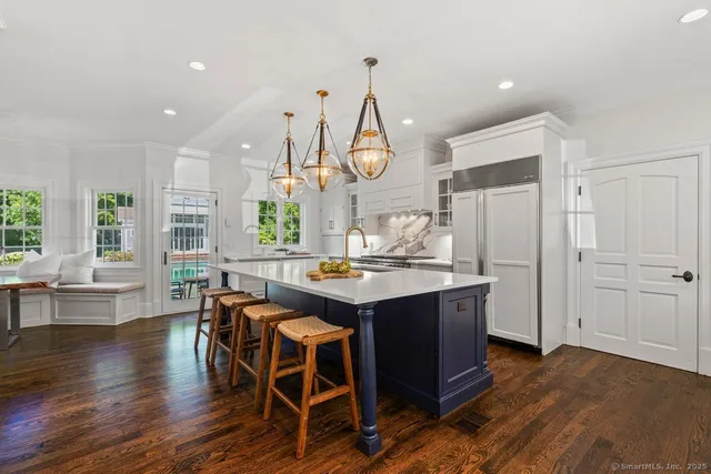 a kitchen with stainless steel appliances granite countertop a table chairs and a wooden floor