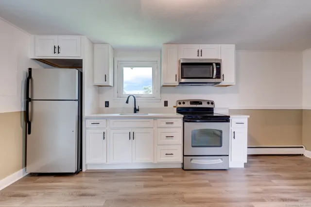 a kitchen with white cabinets stainless steel appliances and a refrigerator