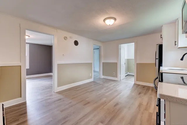 an empty room with wooden floor and entrance to ceiling window