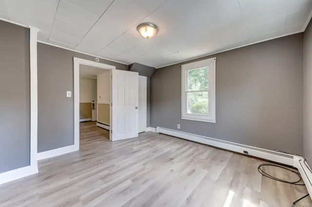 an empty room with wooden floor closet and windows