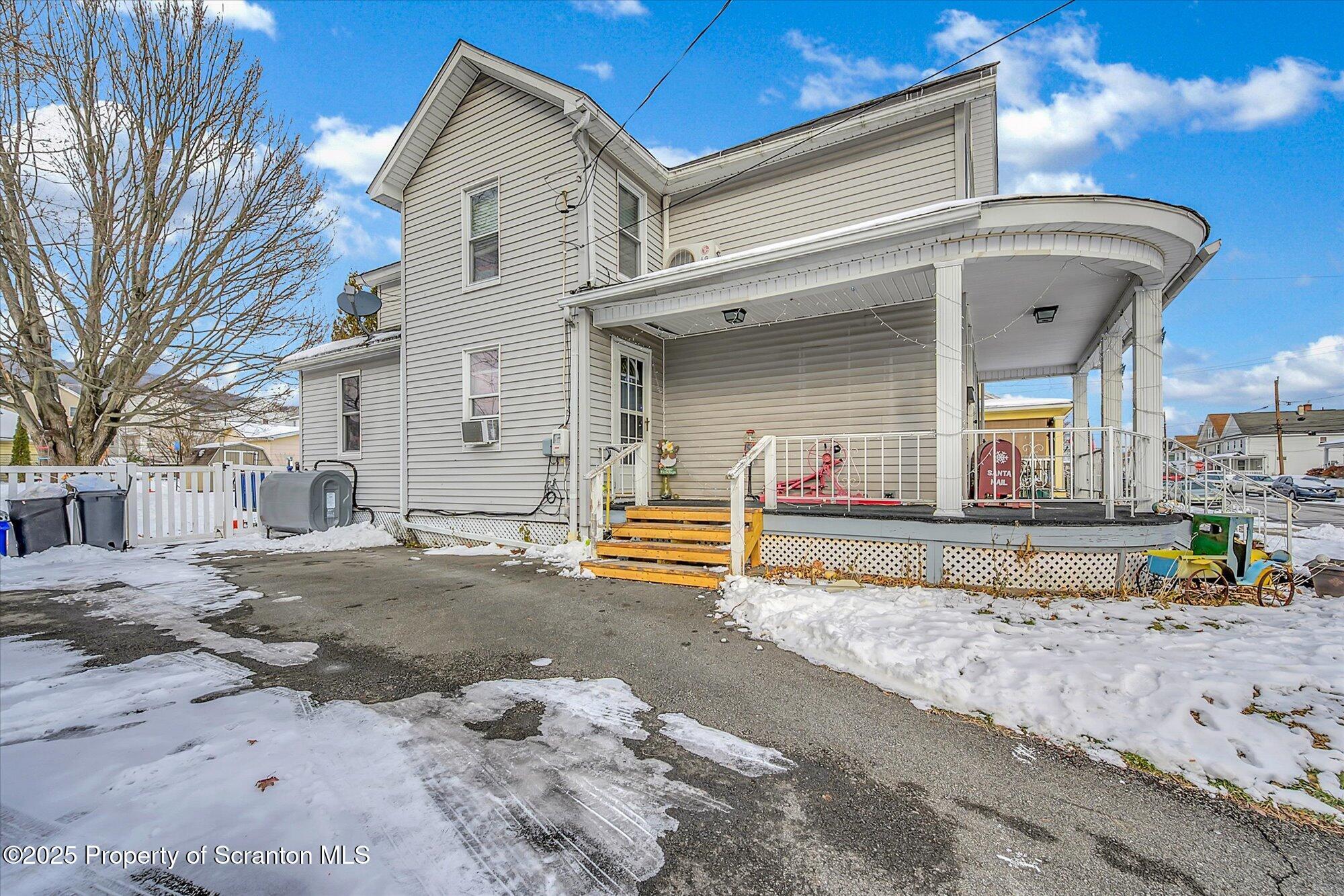 219 1st Street Olyphant, PA 18447 - Photo 5 of 43 a view of a white house with large outdoor space and a car parked in front of it