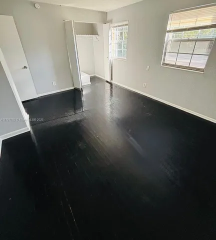 a view of an empty room with wooden floor and a window