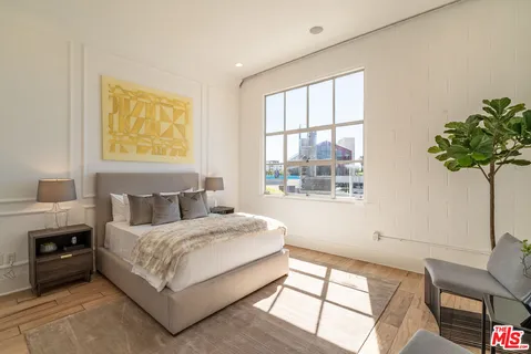 a bedroom with a bed lamp and a large window