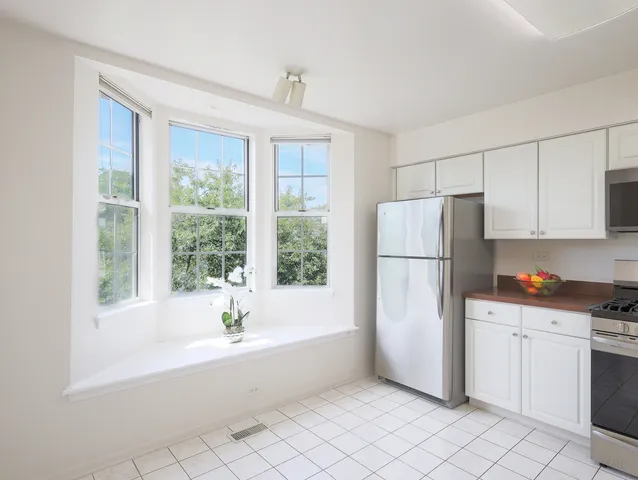 a kitchen with white cabinets and refrigerator