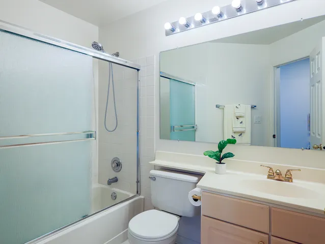 a bathroom with a sink a toilet a mirror a vanity and shower
