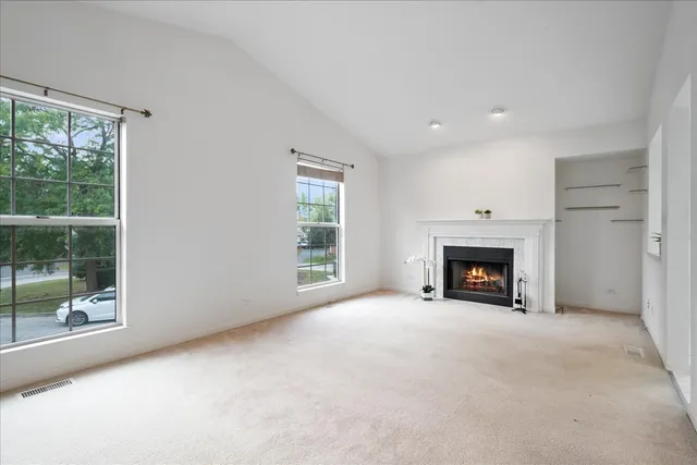 an empty room with windows and fireplace