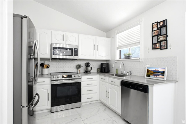 7989 Washington Road Magna, UT 84044 - Photo 7 of 30 Modern kitchen featuring white cabinetry, stainless steel appliances, and a hexagon tile backsplash