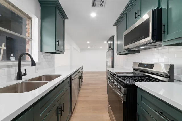 a kitchen with kitchen island stainless steel appliances a sink a stove and a refrigerator