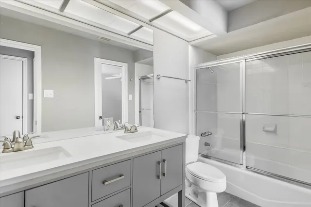 a bathroom with a double vanity sink toilet mirror and shower