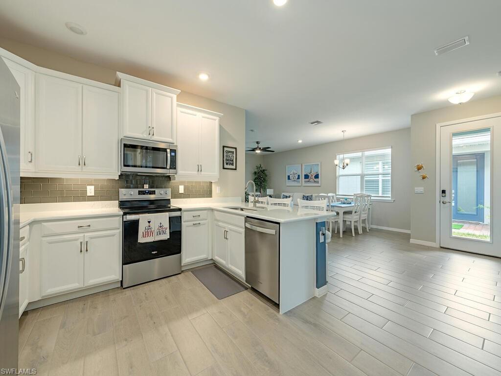 1209 Enbrook Loop Naples, FL 34114 - Photo 5 of 15 Kitchen with appliances with stainless steel finishes, light hardwood / wood-style flooring, sink, kitchen peninsula, and white cabinetry