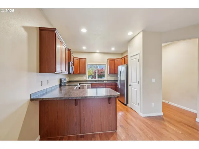 a kitchen with stainless steel appliances granite countertop a sink a refrigerator and a granite counter tops with wooden floors