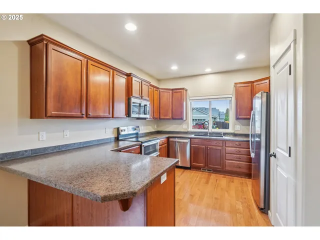 a kitchen with stainless steel appliances granite countertop a sink window and cabinets