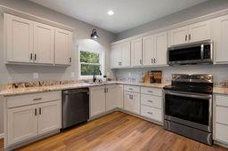 146 Hackney Trail Ellijay, GA 30536 - Photo 12 of 26 a kitchen with granite countertop white cabinets a sink and dishwasher with wooden floor