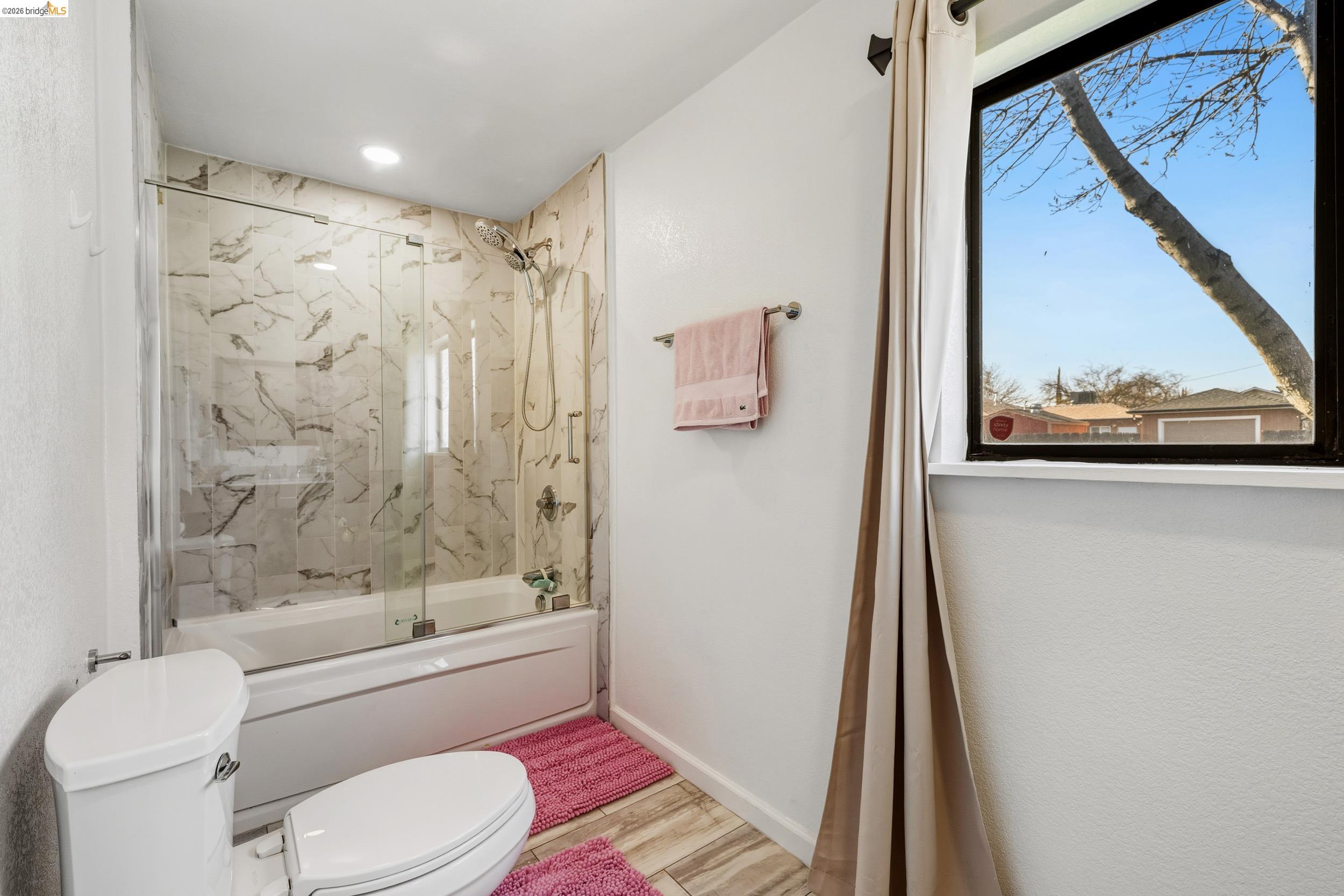 1704 East Street Tracy, CA 95376 - Photo 14 of 29 Bathroom with enclosed tub / shower combo and light wood-style flooring