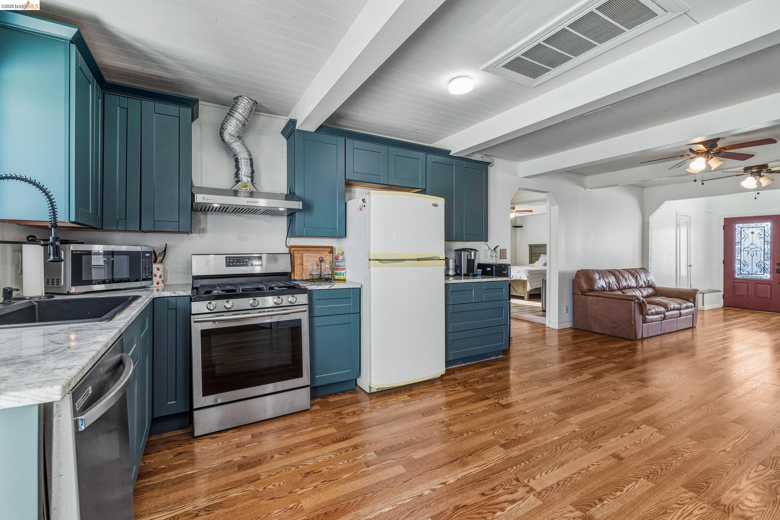 1704 East Street Tracy, CA 95376 - Photo 5 of 29 Kitchen with stainless steel appliances, beamed ceiling, arched walkways, ceiling fan, and light wood-style floors