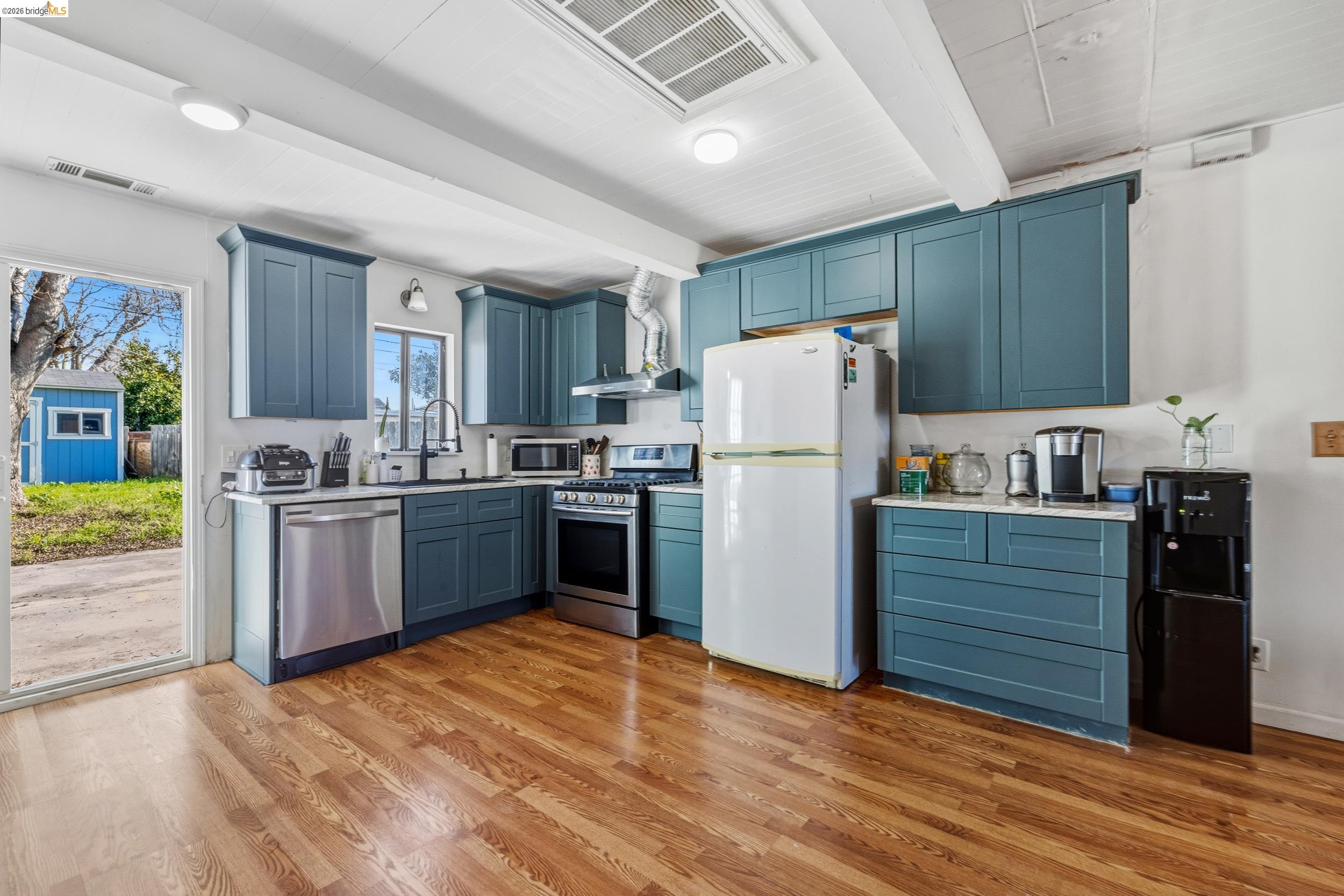1704 East Street Tracy, CA 95376 - Photo 6 of 29 Kitchen featuring blue cabinetry, stainless steel appliances, beamed ceiling, and light wood finished floors