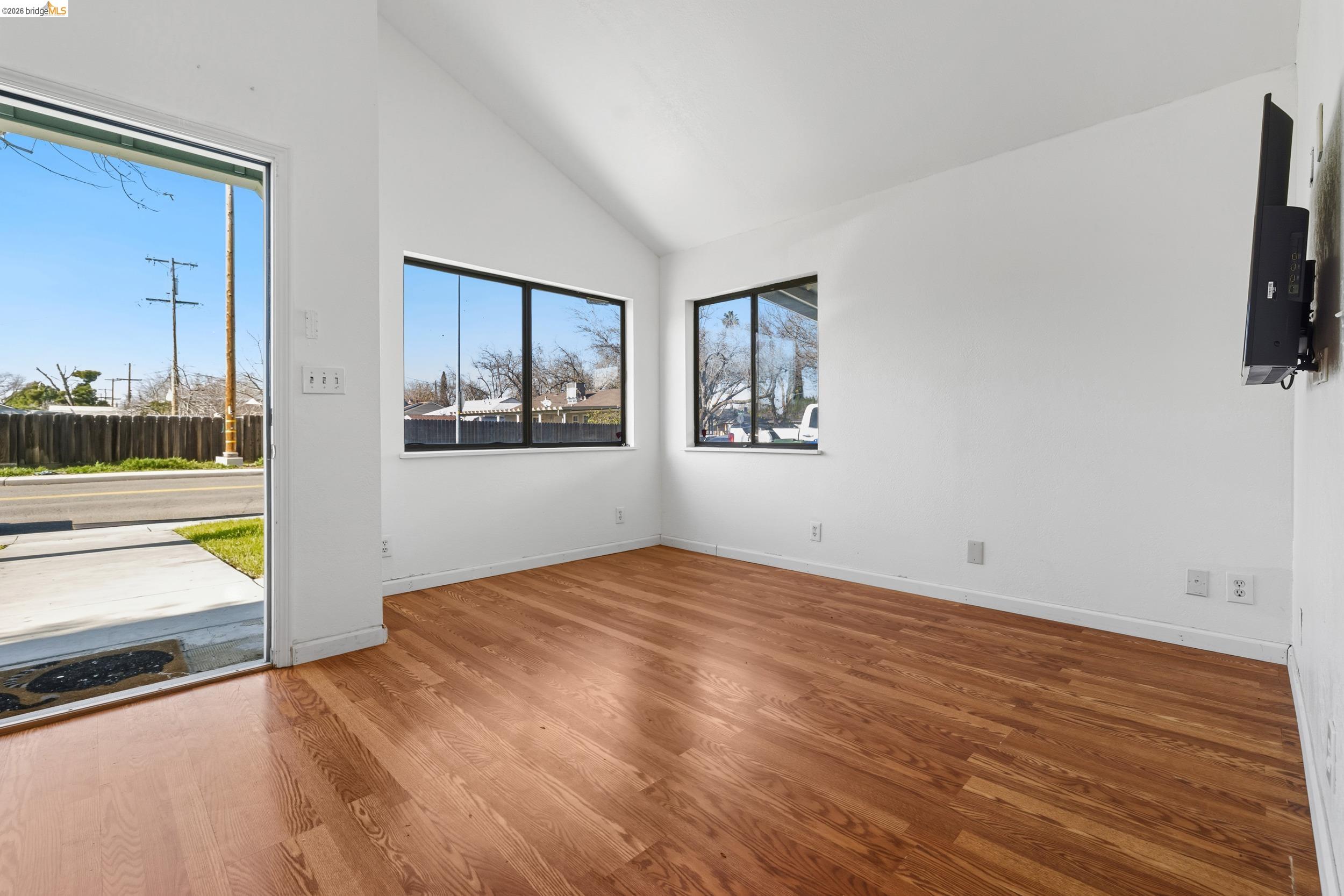 1704 East Street Tracy, CA 95376 - Photo 9 of 29 Spare room featuring high vaulted ceiling and wood finished floors