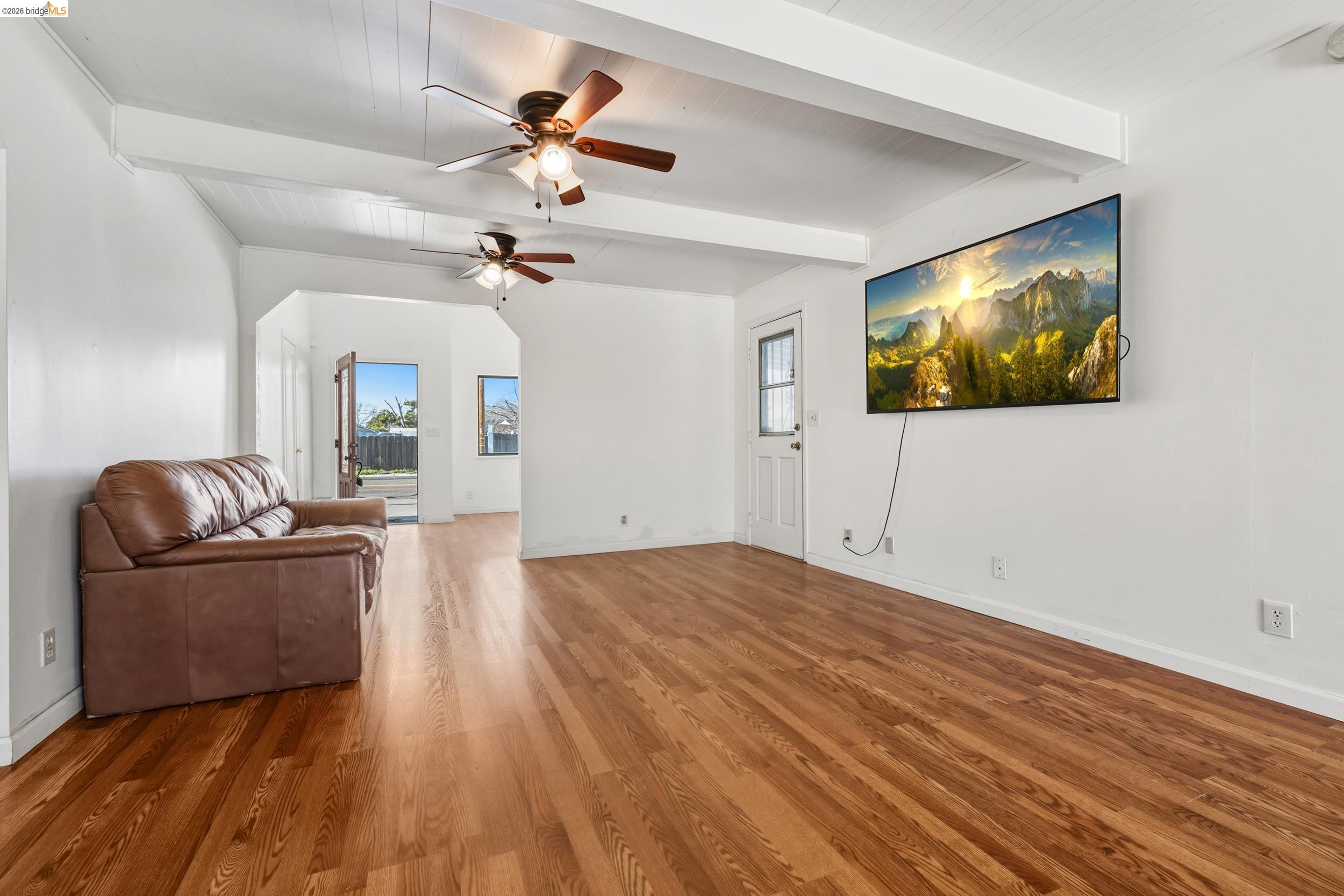 1704 East Street Tracy, CA 95376 - Photo 10 of 29 Unfurnished living room with beamed ceiling, ceiling fan, and wood finished floors